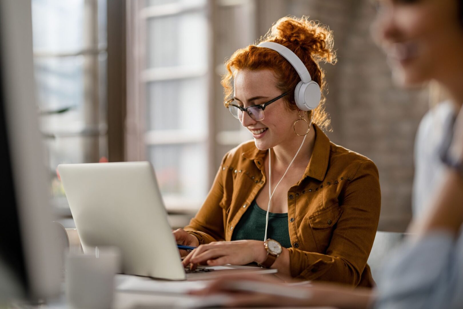 smiling businesswoman listening to music with headphones on computer